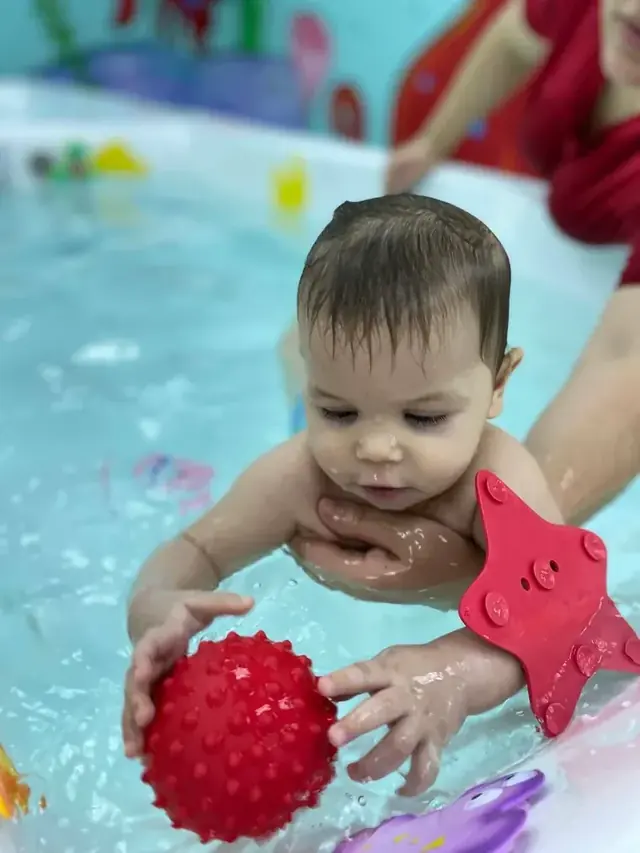 Малыш играет с мячом в воде