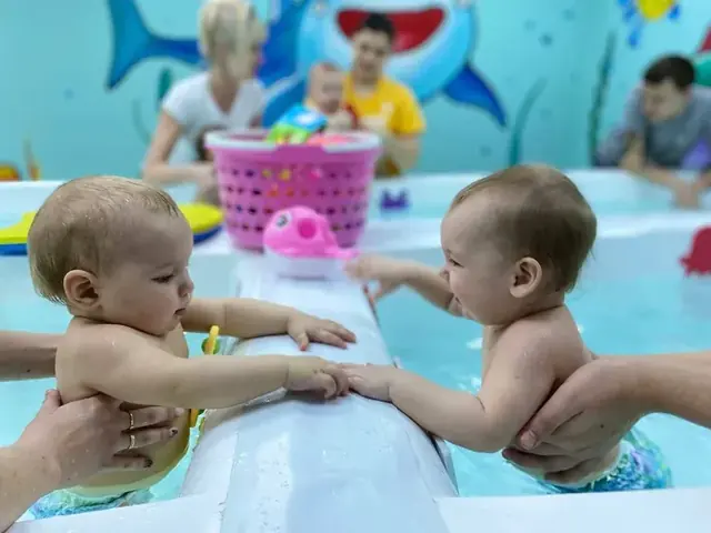 Двое малышей у бортика бассейна